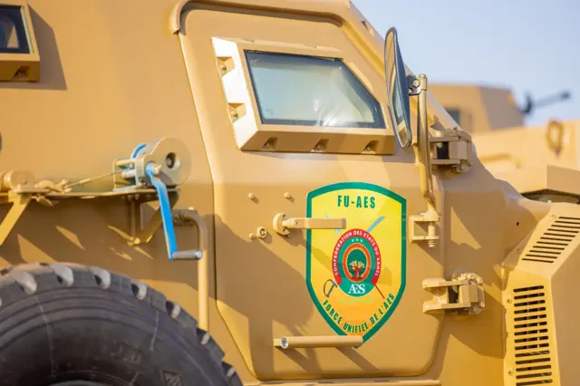 Un véhicule militaire de couleur jaune sur lequel on voit une affiche portant l'indication FU- AES.