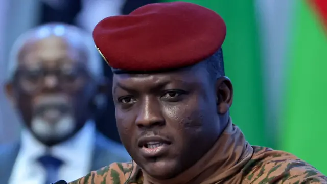 Portrait du capitaine Ibrahim Traoré en tenue militaire beige et béret rouge, lors d'une intervention télévisée.