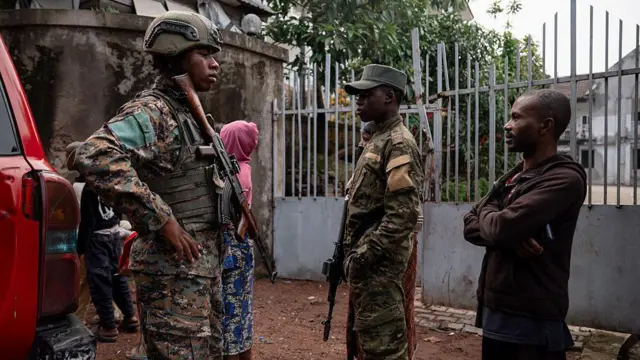Deux militaires en tenue de combat accompagnés d'un civil, dans une zone de tension